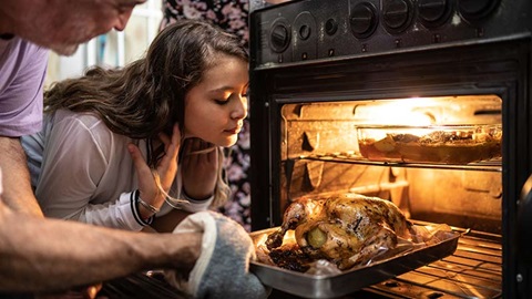 man en vrouw halen gebraden kip uit de oven